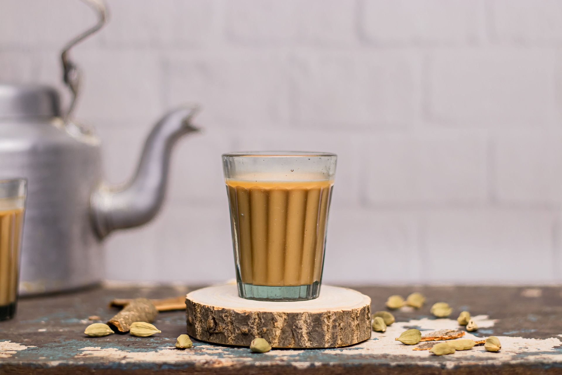 Indian chai in glass cups with metal kettle and other masalas to make the tea.